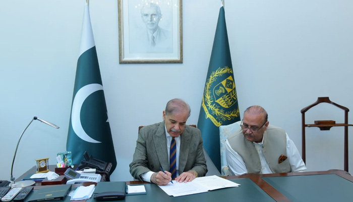 Prime Minister Shehbaz Sharif signs on a summary after selection of caretaker prime minister with Opposition Leader Raja Riaz seated next to him at the PM Office in Islamabad on August 12, 2023. — PM Office