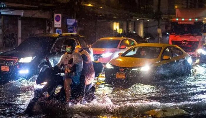 Motorists make their way along a flooded street after heavy rain in Bangkok. — AFP/File