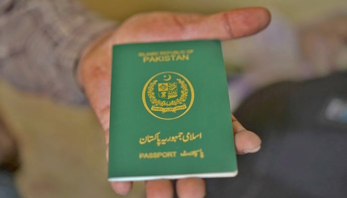 The image shows a man holding a Pakistani passport. — AFP/File