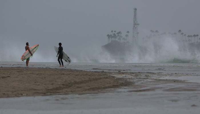 Sörfçüler, 20 Ağustos 2023'te California, Long Beach'te tropik fırtına Hilary yaklaşırken Belmont Shore Beach'te çarpan dalgalara bakıyor.  — AFP