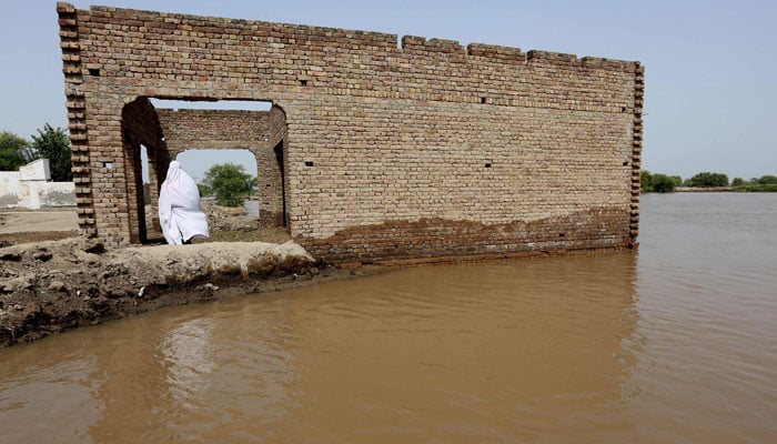 A burqa-clad woman waits for the rescue boat at the flood affected area in Bahawalnagar of Punjab province on August 26, 2023. — AFP