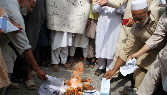 Citizens burn electricity bills as they are holding a protest demonstration against the highly inflated electricity bills, held at Gunj Chowk in Peshawar on Saturday, August 26, 2023. — PPI