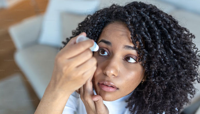 A woman treats her eye with eye drops. — Unsplash/File