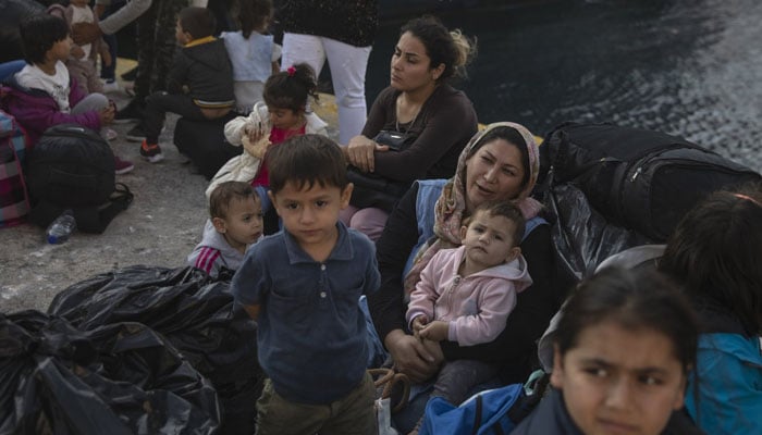 Refugees wait for a bus from Greece to Belgium. — AFP