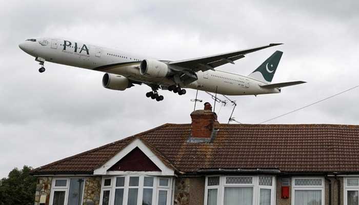 A Pakistan International Airlines (PIA) Boeing 777 comes in over houses to land at Heathrow Airport in west London on June 8, 2020. — AFP