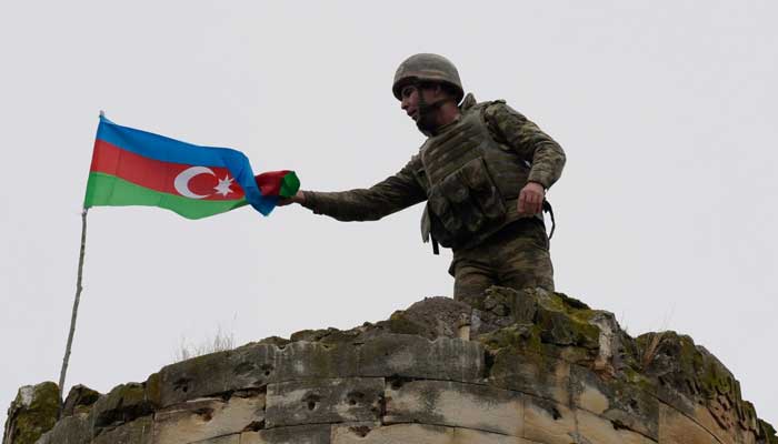 An Azerbaijani soldier attaches a national flag on a tower outside the town of Fuzuli, Azerbaijan, Nov 26, 2020. — AFP