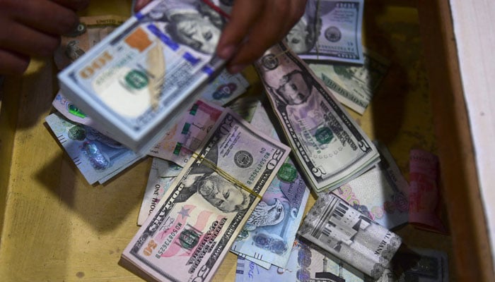 A dealer collect US dollars at a money exchange market in Karachi on January 26, 2023. — AFP