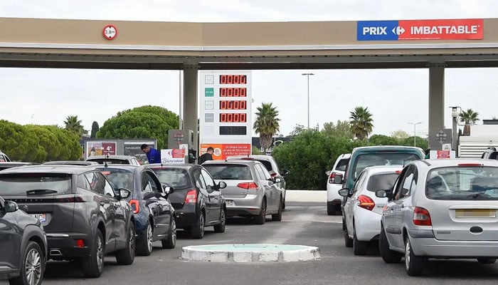 Drivers line up as they wait at a Carrefour fuel station in Lattes, near Montpellier, southern France on October 10, 2022. — AFP