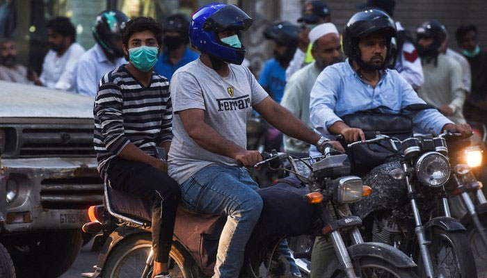 Motorists riding motorbikes along a streetwear facemasks as a preventive measure against the Covid-19 coronavirus, in Karachi on October 29, 2020. — AFP/Files
