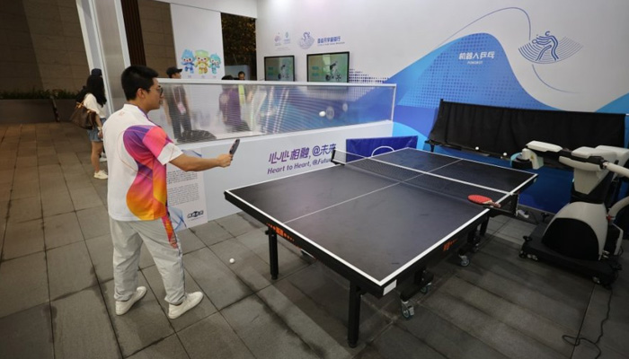Zhejiang eyaleti Hangzhou'daki Asya Oyunları Köyü'nde bir adam robotla masa tenisi oynuyor, 12 Eylül 2023. — VCG