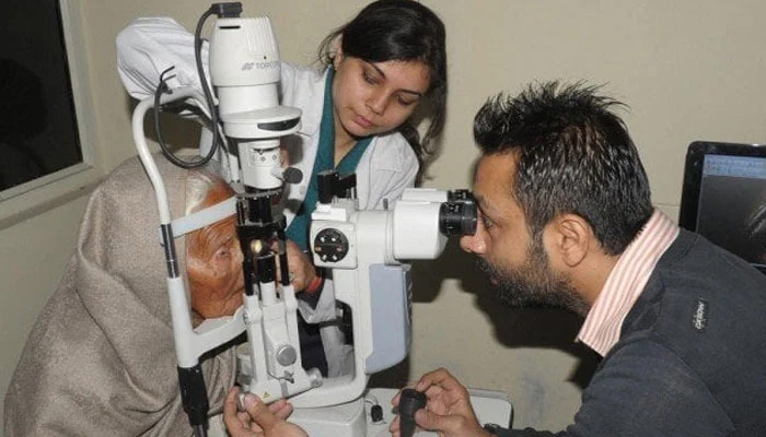 A doctor is checking the eyes of an old woman. — AFP/File