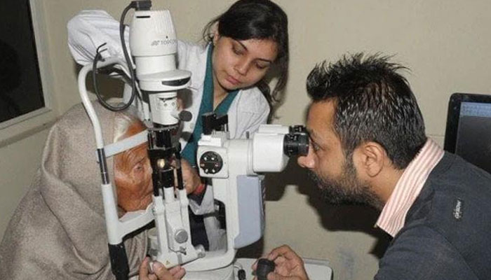A doctor is checking the eyes of an old woman. — AFP/File
