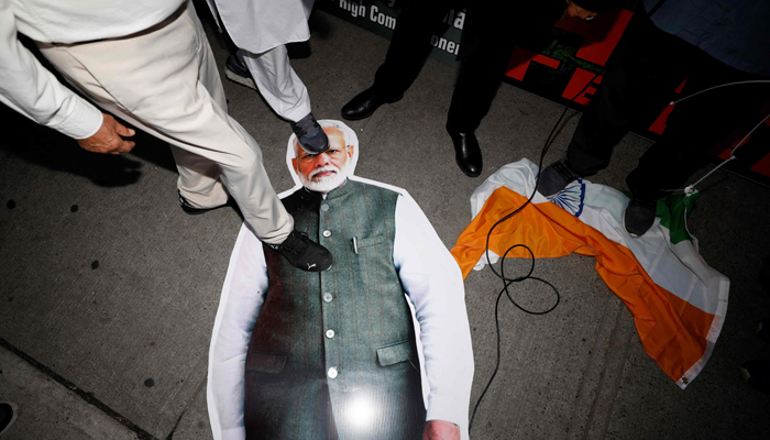 25 ستمبر 2023 کو سکھ رہنما ہردیپ سنگھ نجار کے قتل میں بھارتی حکومت کے مبینہ ملوث ہونے کے بارے میں بیداری پیدا کرنے کے لیے ٹورنٹو میں بھارتی سفارت خانے کے باہر سکھوں کی ریلی کے دوران لوگ مودی کی تصویر والے پوسٹر کو خراب کر رہے ہیں۔ - AFP