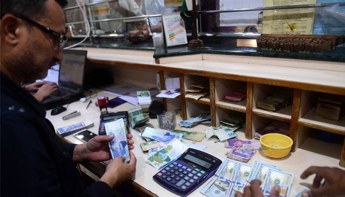 ایک کرنسی ایکسچینج ڈیلر اس غیر تاریخ شدہ تصویر میں 1000 روپے کے نوٹ گن رہا ہے۔  — اے ایف پی/فائل
