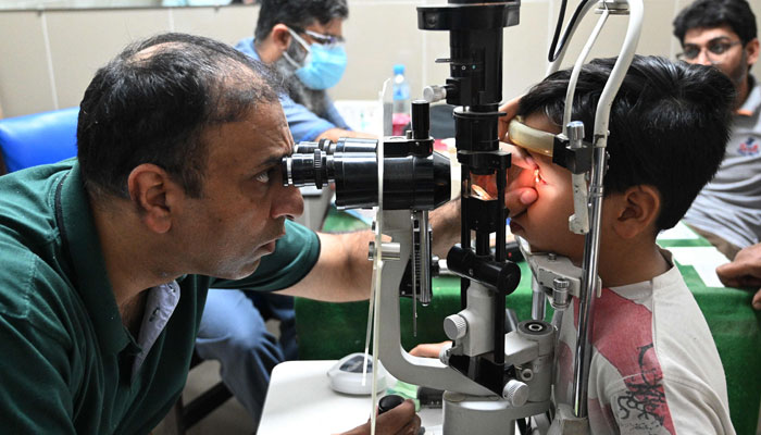 A doctor examines a boy suffering from an eye infection at a hospital in Rawalpindi on September 28, 2023. — AFP
