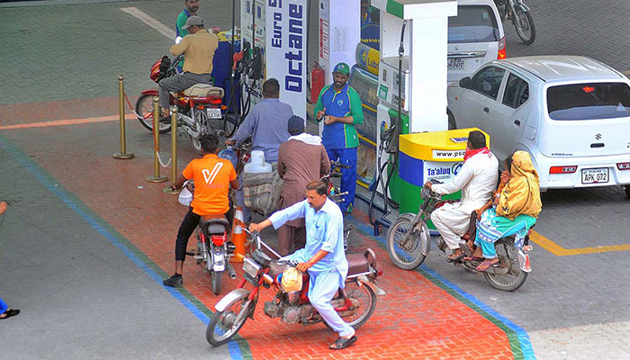 Motorcyclists can be seen at a petrol pump in Multan, on July 19, 2023. — APP