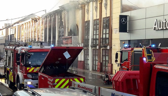This handout photograph taken and released on October 1, 2023 by the 112 Emergency Services of the Murcia Region shows firefighters spraying the facade of the Teatre nightclub as at least thirteen people were killed in a fire, in Murcia.—AFP