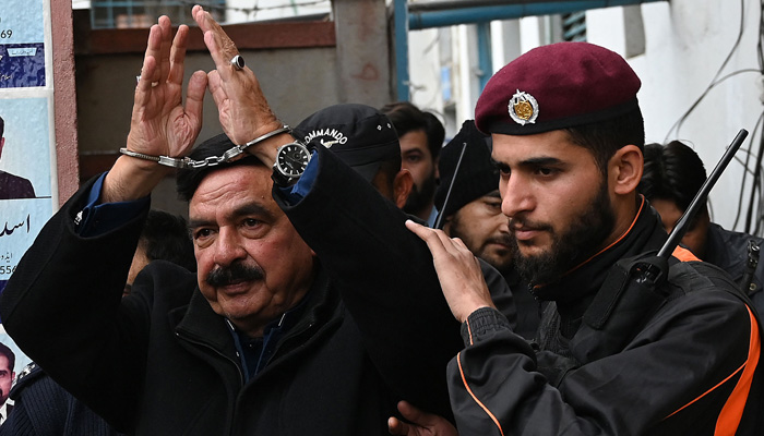 Police officials escort Pakistan´s former interior minister Sheikh Rashid Ahmed (C) to present him before a court in Islamabad on February 2, 2023. — AFP