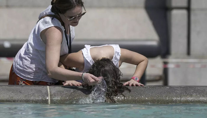 A person wets her hair in a fountain in London’s Trafalgar Square after record-setting high temperatures in the UK. — X@aaronchown