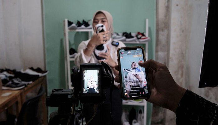 A staff of a small shoe manufacturer shows their new products to make an introductory video to be posted on social media in Bogor, West Java. — AFP