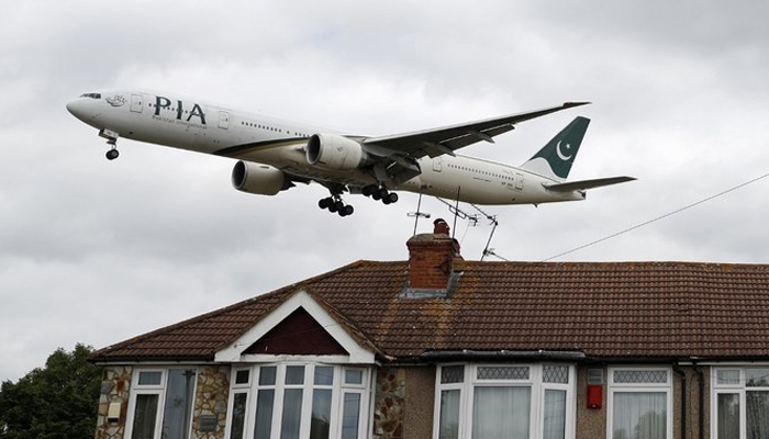 A Pakistan International Airlines (PIA) Boeing 777 comes in over houses to land at Heathrow Airport in west London on June 8, 2020. — AFP