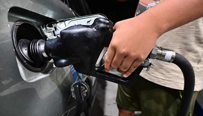 A man pumps gas into a vehicle at a petrol station on October 2, 2023 in Alhambra, California. — AFP