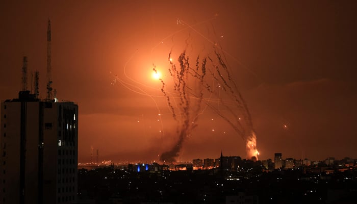 A salvo of rockets is fired by Hamas from Gaza as an Israeli missile launched from the Iron Dome attempts to intercept the rockets over the city of Netivot in southern Israel on October 8, 2023. — AFP