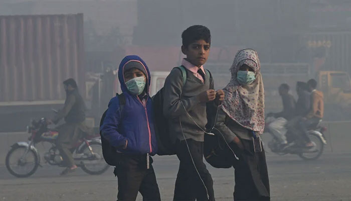 یکم دسمبر 2022 کو لاہور میں شدید سموگ کے درمیان بچے سکول جاتے ہیں۔ - اے ایف پی