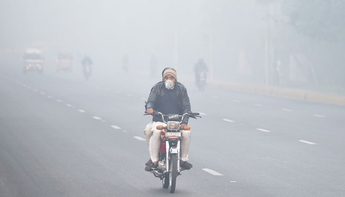 Commuters on a road in Lahore during smog in this 2019 file image. — AFP