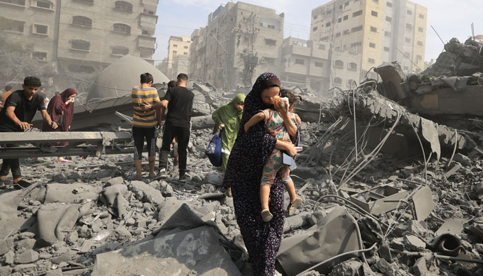 Palestinians in Gaza city inspect the damage following an Israeli airstrike, 9 October 2023. — AFP