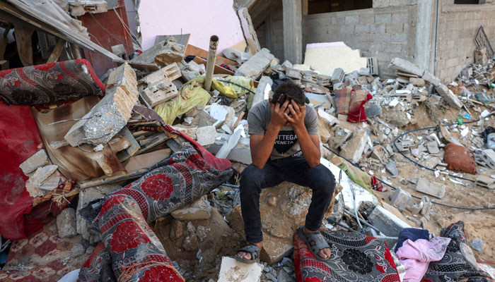 A Palestinian youth reacts as he sits on the rubble of a destroyed home following an Israeli military strike on the Rafah refugee camp, in the southern Gaza Strip on October 15, 2023, — AFP