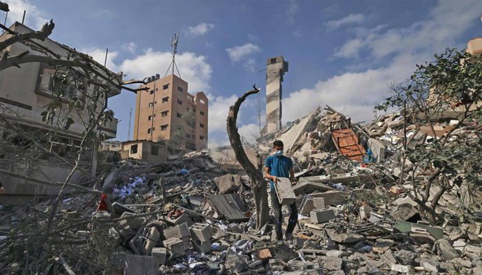 A Palestinian youth looks for salvageable items amid the rubble of the Kuhail building, which was destroyed in an early morning Israeli airstrike on Gaza City on Tuesday. — AFP