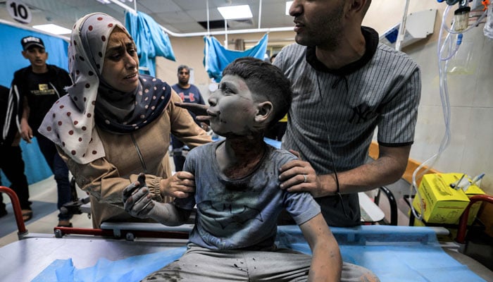 A woman and a man attend to a child injured in Israeli bombardment while awaiting treatment at a trauma ward at Nasser hospital in Khan Yunis in the southern Gaza Strip on October 24. — AFP