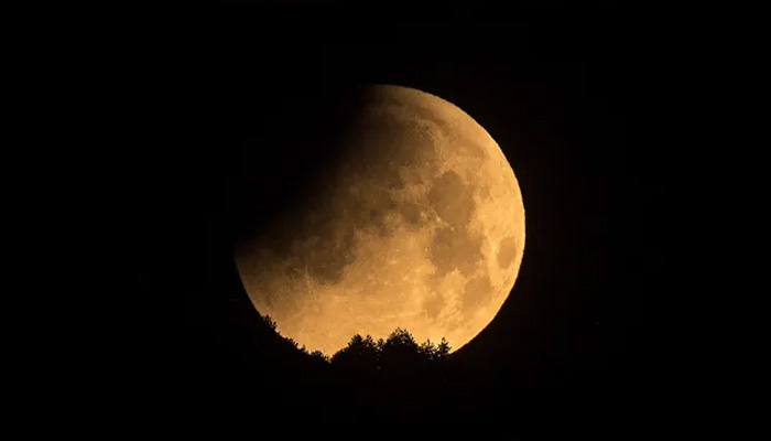 A lunar eclipse occurring as a shadow falls on the moon seen through a telescope. — AFP
