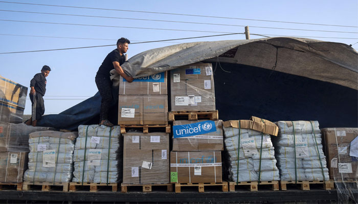 A man unloads humanitarian aid on a convoy of lorries entering the Gaza Strip from Egypt via the Rafah border crossing on October 21, 2023. — AFP