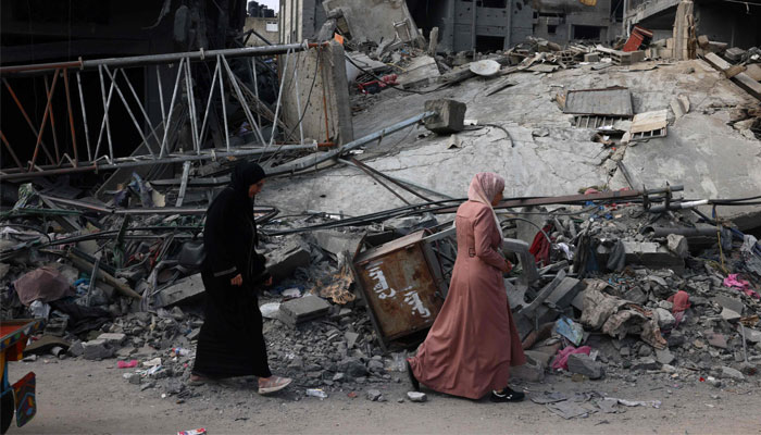 Women walk past a destroyed building in the aftermath of the Israeli bombing in Rafah in the southern Gaza Strip on October 28, 2023. — AFP