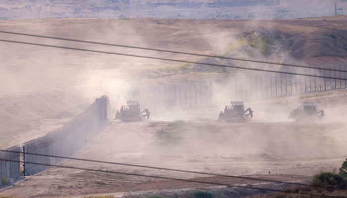 A picture taken from southern Israel along the border with the Gaza Strip shows Israeli army bulldozers crossing the border into Gaza, on October 29, 2023, amid ongoing battles between Israel and Palestine. — AFP