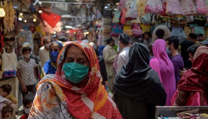 A masked woman shops at a market in Rawalpindi. — AFP/File