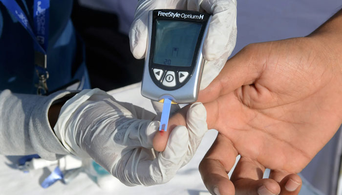 A health care worker conducting a diabetes test on a patient. — AFP/File