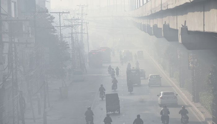 Motorists are on their way during smoggy conditions in Lahore. — Online/File