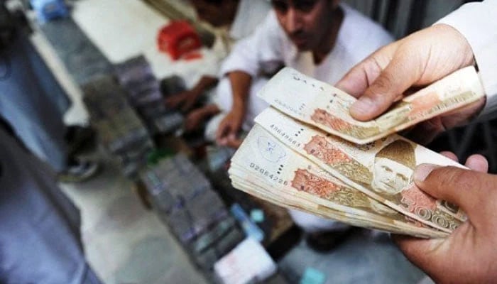 A dealer counts banknotes of Rs5000 at a currency market in Pakistan. — AFP/File