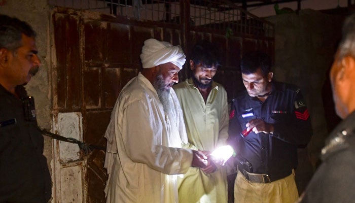 Police personnel check the documents of detained Afghan refugees during a search operation to identify allegedly illegal immigrants, in the outskirts of Karachi on November 11, 2023. — AFP