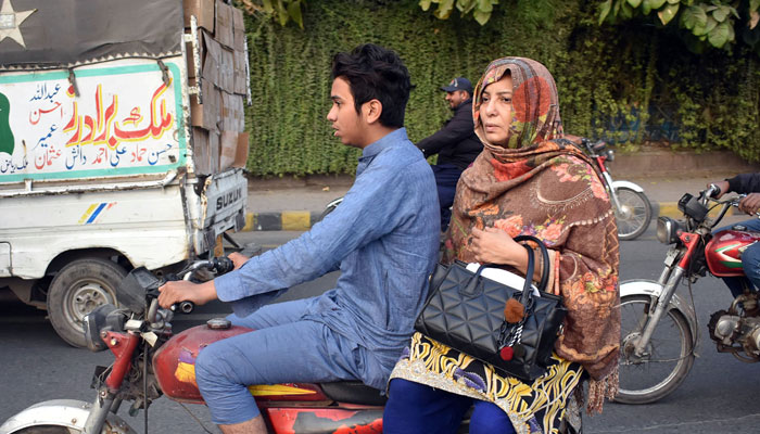 A young boy is carrying his mother on a motorcycle in Lahore. — Online/file