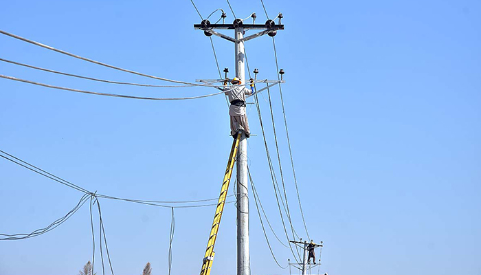 Workers seen on an electric pole in Islamabad, on October 26, 2023. — APP