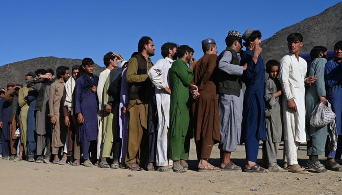 Afghan refugees stand in a queue while waiting to receive food from a local charity at a makeshift camp upon their arrival from Pakistan, near the Afghanistan-Pakistan Torkham border in Nangarhar province on November 12, 2023. — AFP