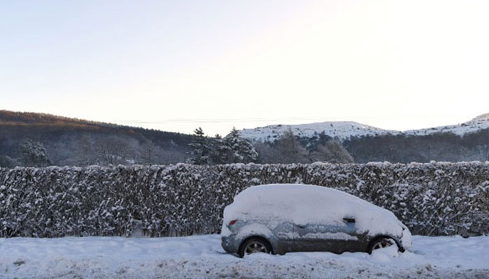 A car lies abandoned following heavy snowfall near Ruthin, north Wales on December 11, 2017. — AFP