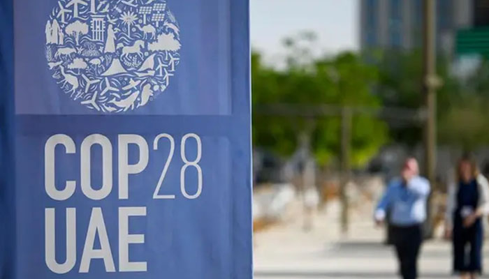 People walk past a COP28 logo ahead of the United Nations climate summit in Dubai on November 28, 2023. — AFP