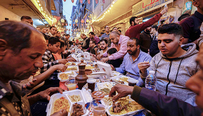 Egyptian Muslims gather in streets lined with long tables to break their Ramadan fast together in a mass iftar meal in Ezbet Hamada in Cairos Matariya suburb. — AFP