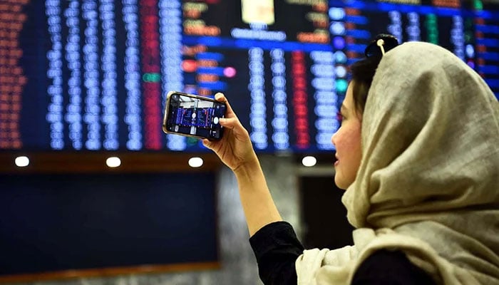 A woman takes pictures of the electronic board displaying data at the Pakistan Stock Exchange in Karachi, on December 21, 2022. — PPI