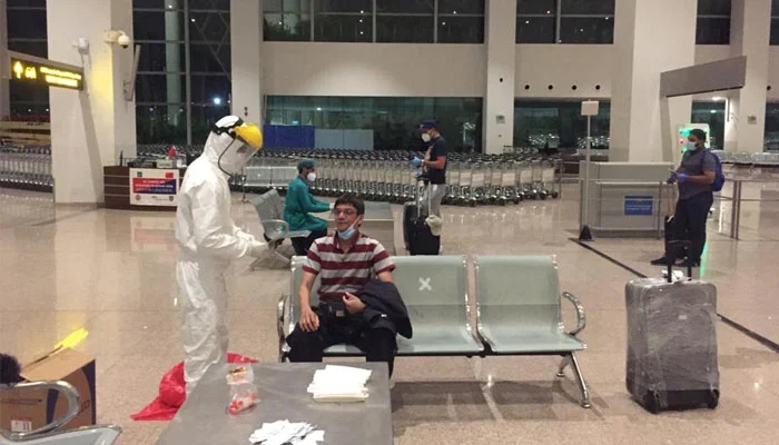 A health worker prepares for COVID-19 testing on a passenger at Islamabad International Airport. — NIH